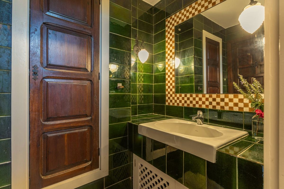 Baño con azulejo verde y espejo de cerámica
