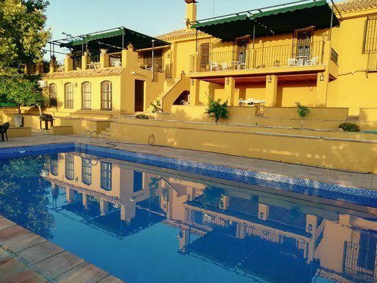 Piscina frente a la fachada amarilla de la casa